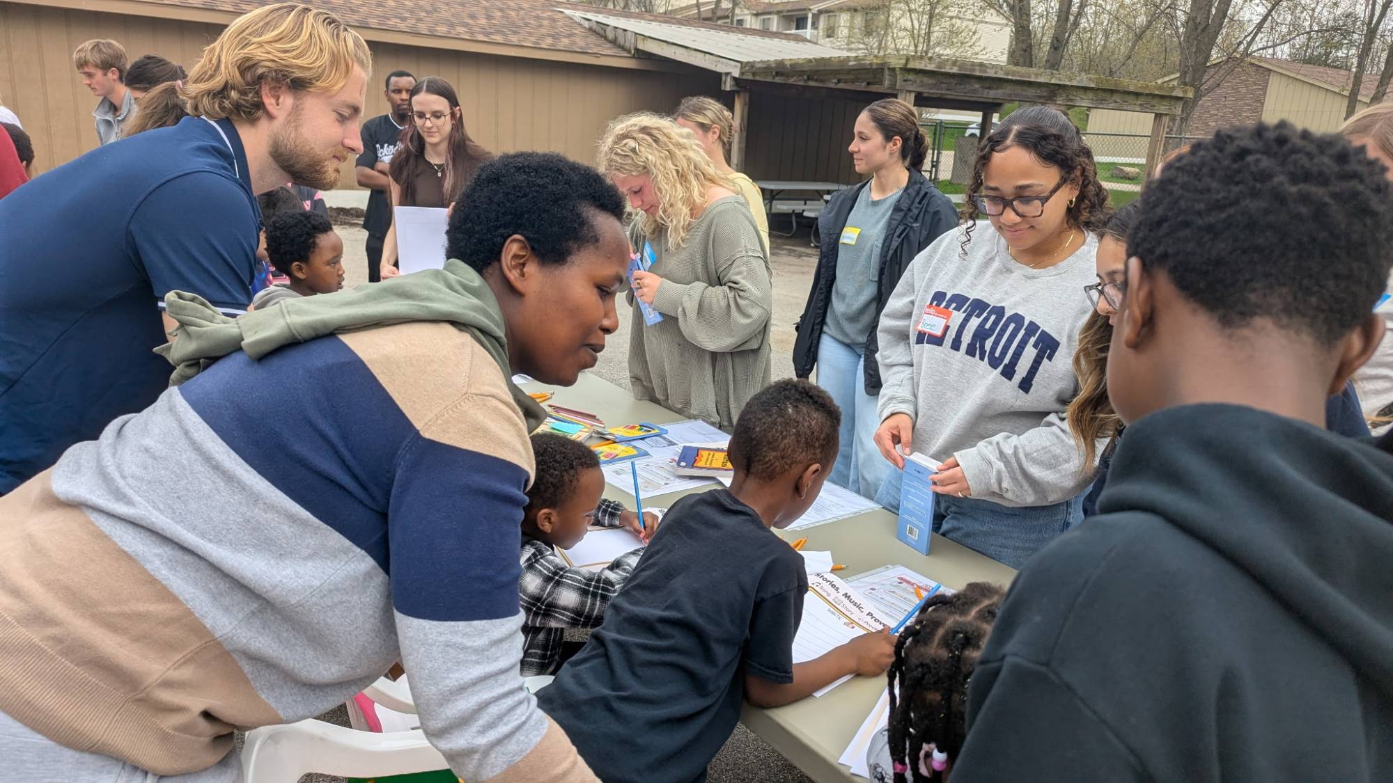 Children and adults smiling, gathered around a table coloring
